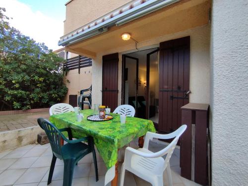 une table et des chaises vertes sur la terrasse dans l'établissement Appartement T2 Saint-Pierre-La-Mer: Terrasse, Parking Privé, Tennis - 4 Pers. - FR-1-795-23, à Fleury