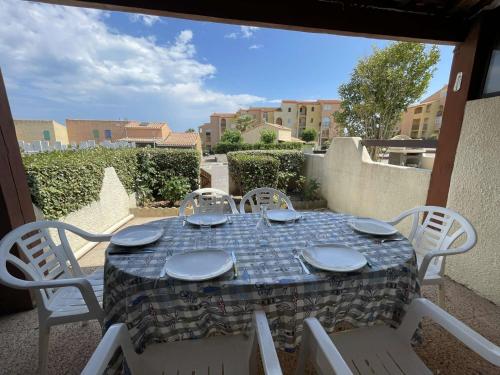 - une table avec des assiettes et des chaises sur la terrasse dans l'établissement Villa T2 Mezzanine, Parking, Proche Plage, 6 Pers – Terrasse Lumineuse et Équipements Complets - FR-1-795-31, à Fleury