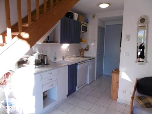 une cuisine avec des placards blancs et un escalier dans l'établissement Villa 7 pers, Narbonne Plage à 400m, 3 ch, terrasses, parking, proche commerces et loisirs - FR-1-795-44, à Narbonne