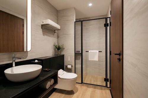 a bathroom with a white sink and a toilet at Quincy House Singapore in Singapore