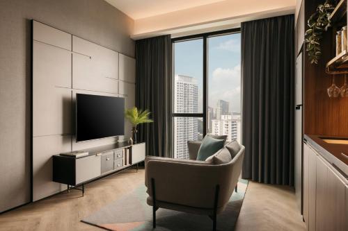 a living room with a tv and a couch and a chair at Quincy House Singapore in Singapore