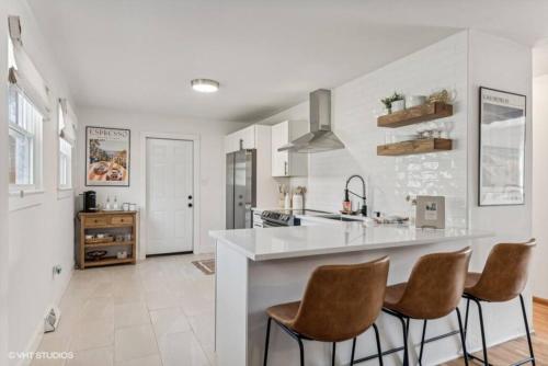 a kitchen with a white counter and some brown chairs at Blocks to Town, Game Room, Firepit, Huge Backyard in New Buffalo