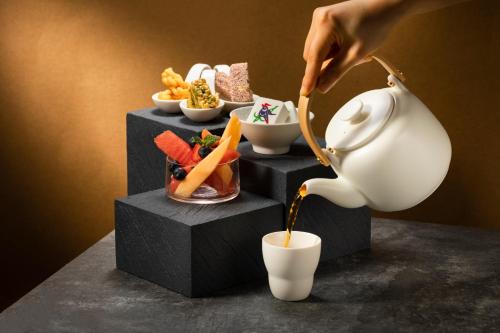 a person pouring coffee into a white tea pot at Four Points by Sheraton Chengdu, High-Tech Zone Exhibition Center in Chengdu