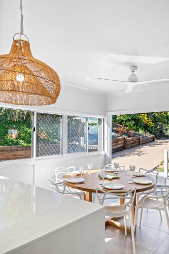 a dining room with a table and chairs and windows at Hill Street House in Yeppoon