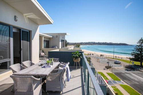 a balcony with a table and chairs and a view of the beach at Mollymook Luxury Beachfront Apartment 10 in Mollymook