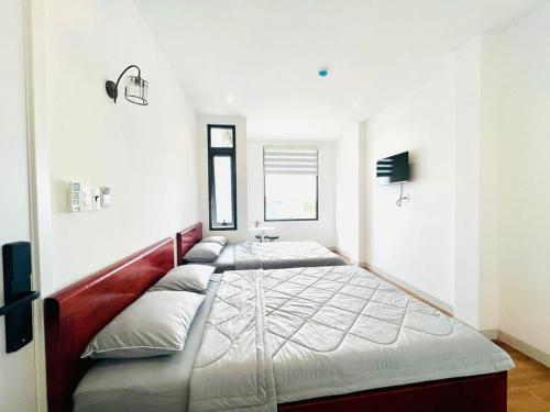 a large bed in a white room with avertisementatronatronatron at Khách sạn triệu nguyễn in Buôn Kô Sir