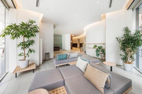 a lobby with a couch and potted plants at Fraser Residence Nankai Osaka in Osaka