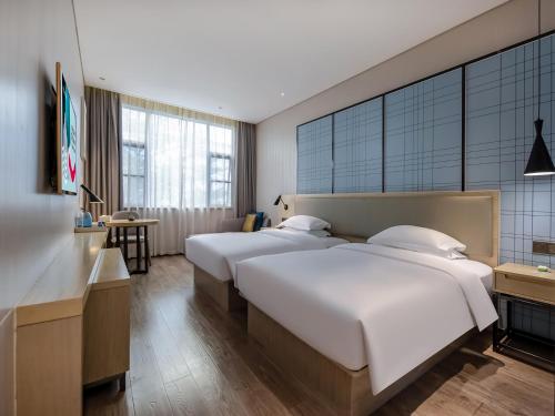 a hotel room with two beds and a desk at Echarm Hotel Nanning the MixC Exhibition Center Metro Station in Nanning