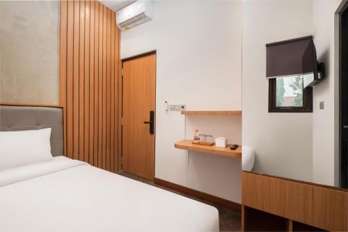 a bedroom with a white bed and a wooden door at Omni Rooms by Sinergi in Semarang