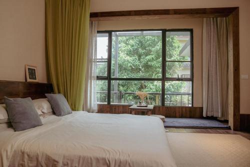 a bedroom with a bed and a large window at Yangshuo Shui Mo Ju courtyard in Yangshuo