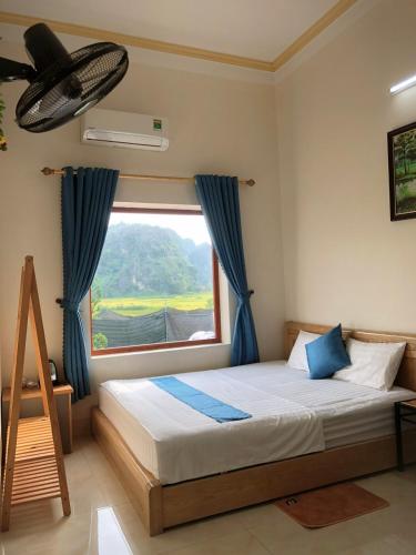 a bedroom with a bed with blue curtains and a window at Cherry homestay in Ninh Binh