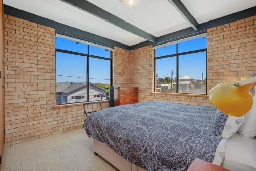 Un dormitorio con una cama en una pared de ladrillos. en 7 Murrah, en Bermagui
