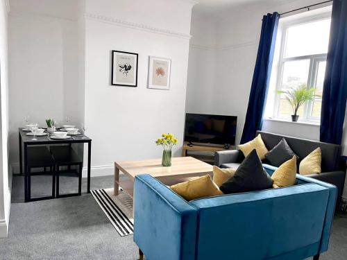 a living room with a blue couch and a table at Spacious 3 Bedroom House in Pallion