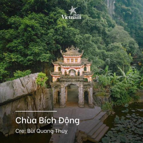 a building in the middle of a river with a bridge at Cherry homestay in Ninh Binh