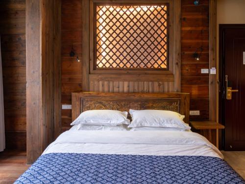 a bed with two pillows in a room with a window at Yangshuo Shui Mo Ju courtyard in Yangshuo