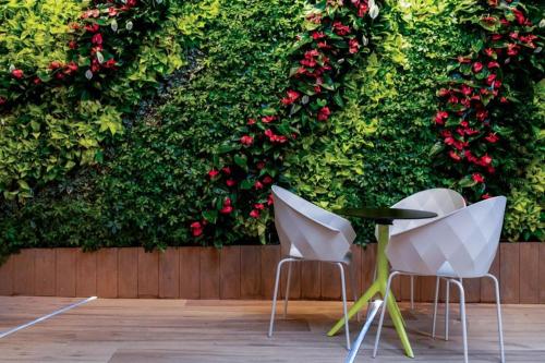 two chairs and a table in front of a wall with roses at OASIS AVENUE-A GDH HOTEL in Hong Kong