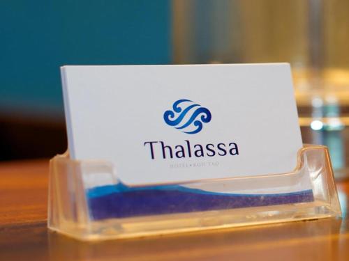 a sign for a thiassa on a wooden table at Thalassa Hotel in Koh Tao