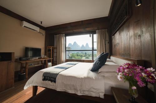 a bedroom with a bed and a large window at Yangshuo Shui Mo Ju courtyard in Yangshuo