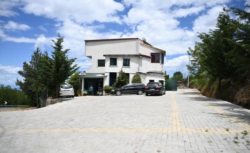 a white building with two cars parked in a parking lot at Joni Restaurant in Pogradec