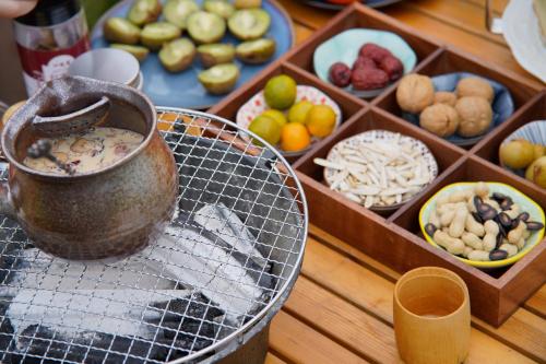 a table with a pot on a grill with fruits and vegetables at Yangshuo Shui Mo Ju courtyard in Yangshuo