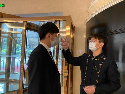 two men wearing face masks in a room at Xiamen Jingmin Central Hotel in Xiamen