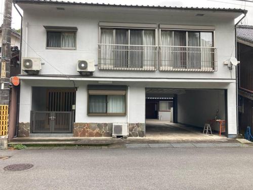 a white house with a balcony and two windows at 寺田旅館一軒家レンタル素泊まり最大15人宿泊可能 4名様まで同一料金 in Mine