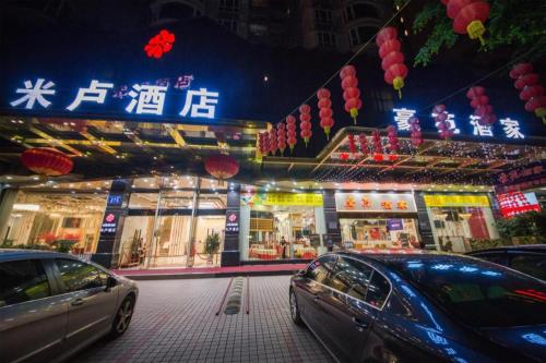two cars parked in front of a store at night at Milu Hotel in Guangzhou