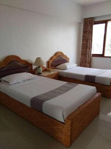 two twin beds in a room with a window at Pailyn Hotel in Sukhothai