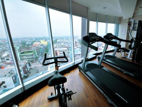 a gym with two tread machines in a room with windows at Hermes Palace Hotel Medan in Medan