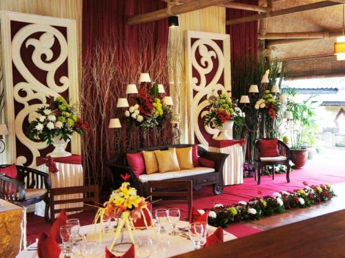 a room with a couch and tables and flowers at Sambi Resort, Spa & Resto in Yogyakarta