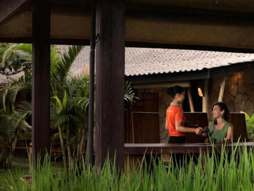 a man and a woman standing at a table with a laptop at Sambi Resort, Spa & Resto in Yogyakarta