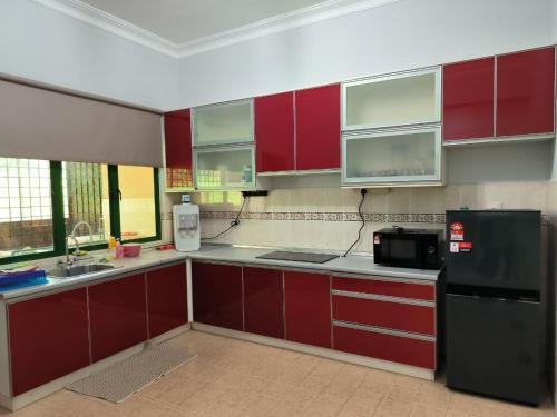 a kitchen with red cabinets and a black refrigerator at Hening Kesuma Homestay in Beranang