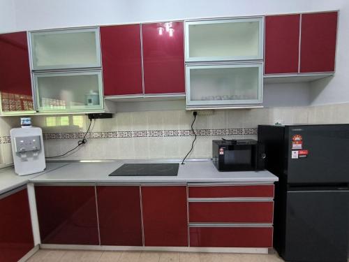 a kitchen with red cabinets and a black refrigerator at Hening Kesuma Homestay in Beranang