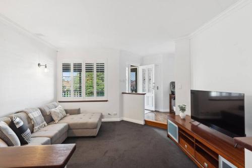 a living room with a couch and a flat screen tv at Beachside Family Friendly Escape at Casa Del Caravel in Mandurah