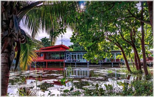 a building with a pond in front of it with trees at BanRai ChernMa Resort in Tak