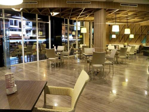 a dining room with tables and chairs in a building at Orchardz Hotel Gajah Mada in Pontianak