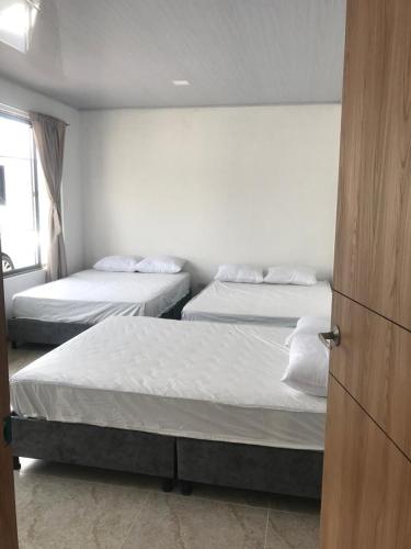 ein Schlafzimmer mit zwei Betten und einer Tür zu einem Zimmer in der Unterkunft Casa Acacías Meta con Piscina y Jacuzzi in Acacías