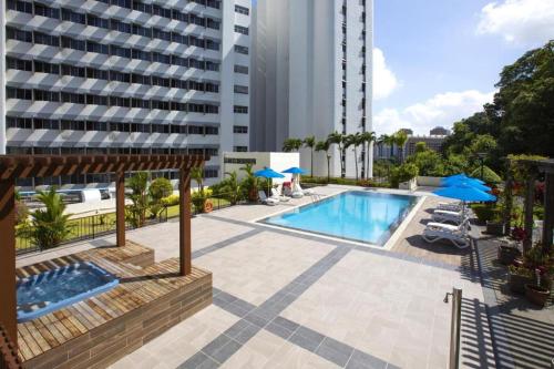 a swimming pool with blue umbrellas and a building at Hotel Miramar Singapore in Singapore