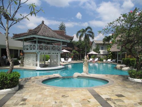 a pool at a resort with a statue in the middle at Ananda Resort Seminyak in Seminyak