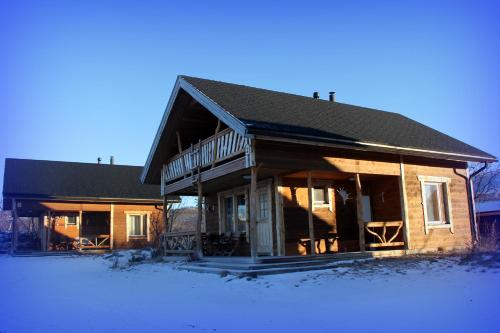 a house with snow on the ground in front of it at Saivaara Cottages in Kilpisjärvi