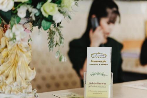 a person talking on a cell phone next to a table with a cake at Aramis Hotel in Nakhon Sawan