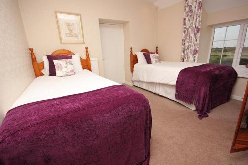 a bedroom with two beds and a window at Lastra Farm Hotel in Amlwch