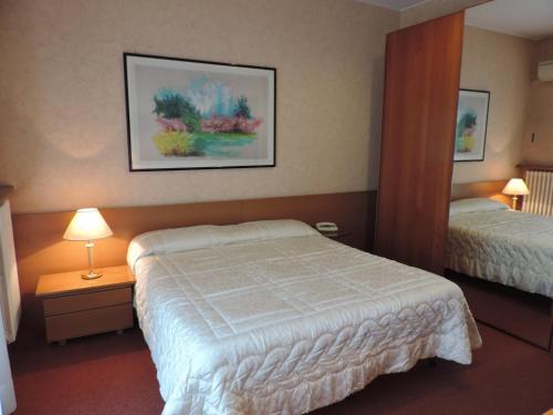 a hotel room with two beds and two lamps at Hotel Gama in Melzo