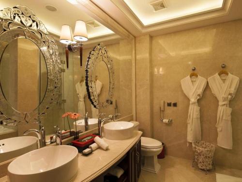 a bathroom with two sinks and a toilet and mirrors at Eden Club House in Tongxiang
