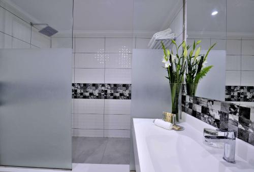 a white bathroom with a sink and a vase of flowers at Kenzi Basma in Casablanca
