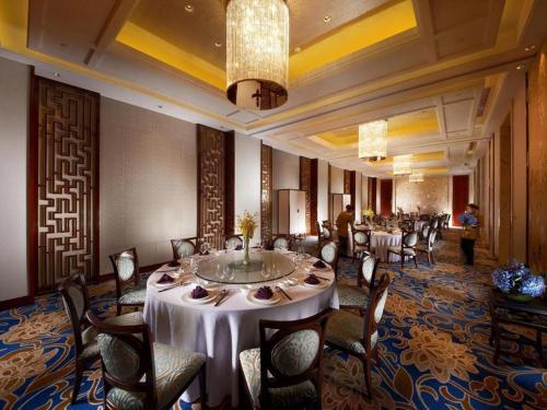 a dining room with tables and chairs and a chandelier at Dongwu New Century Grand Hotel Huzhou in Huzhou