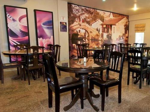 a dining room with tables and chairs and a painting at Traders Inn Brunei in Bandar Seri Begawan