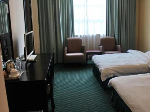a hotel room with two beds and a desk and chairs at Traders Inn Brunei in Bandar Seri Begawan