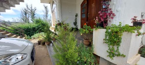 a car parked in front of a house with potted plants at Anya Paradise in Ooty