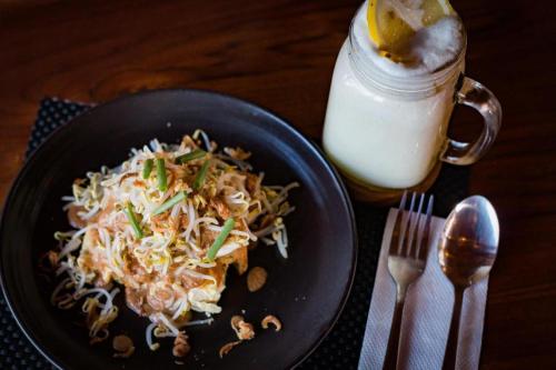 a plate of food on a table next to a glass of milk at Hadi Poetra Hotel in Kuta